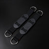 Two black adjustable shoulder straps with silver metal D-rings, displayed diagonally on a dark black background.