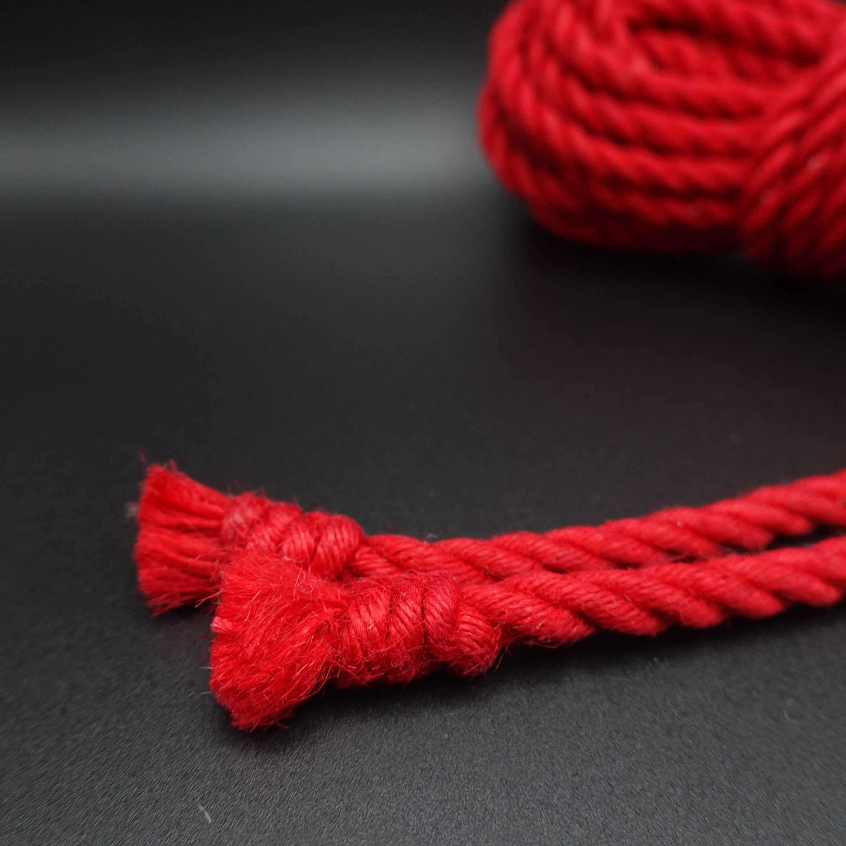 Close-up of red jute shibari rope showcasing its vibrant crimson color and natural texture.
